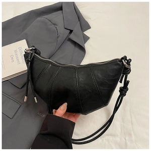 Detail of black crescent hobo bag featuring knotted shoulder strap and pleated texture
