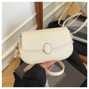 Detail of cream white leather shoulder bag featuring textured flap and silver hardware
