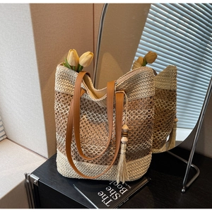 Détail du sac de plage tissé montrant la texture bicolore, la bandoulière et le gland perlé