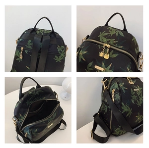 Detail view of black backpack with green bamboo leaves and golden metal zippers
