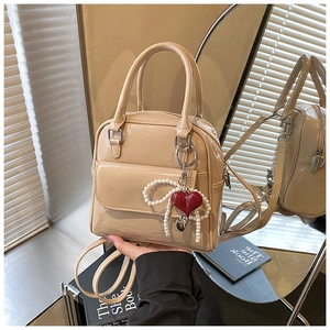 Detail of apricot patent leather mini bag with heart pearl charm and glossy finish