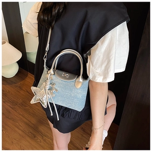 Detail of light blue crossbody bag with silver bow buckle and star charm shown on model
