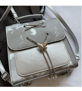 Close-up of silver satin backpack featuring metallic butterfly buckles and lace-up details