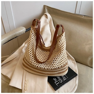 Detail of beige crochet tote bag with brown leather straps on a minimalist background