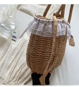 Detail of handmade straw bag with white lace trim and colorful beads on white fabric