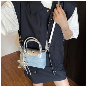 Detail of light blue denim crossbody bag with silver bow and sparkling star pendant