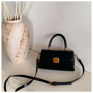 Detail einer Vintage-Handtasche aus schwarzem Leder mit Goldverschluss und Deko