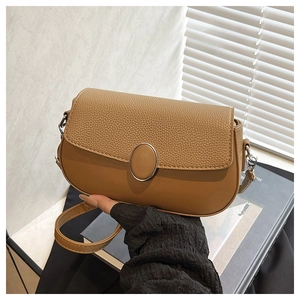 Detail of caramel crossbody bag featuring textured pebble leather and oval buckle closure