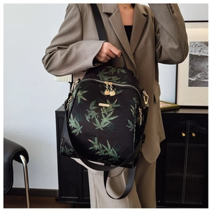 Detail of a chic black backpack with green bamboo leaf print and golden metal zippers