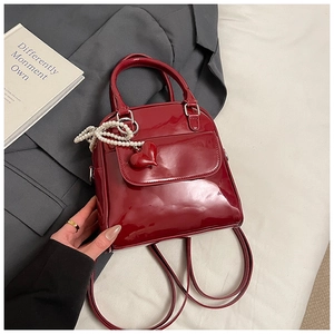 Close-up of a red patent leather mini backpack with pearl chain and heart charm detail