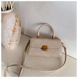 Detail einer minimalistischen beigen Handtasche mit poliertem Leder und goldenem Metallschloss