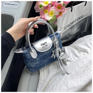 Close-up of denim shoulder bag with silver bow buckle and balloon dog charm in car