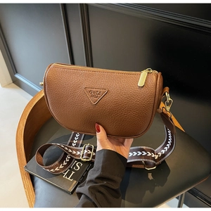 Detail of brown lychee leather pillow bag with woven strap and golden hardware accents