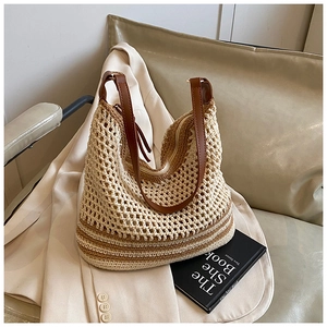 Detail of hollow woven tote bag with brown PU straps on a beige blazer and sofa