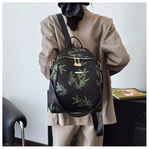 Close-up of bamboo leaf pattern backpack with golden metal zippers and logo plate