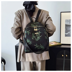 Rear view of woman wearing black floral backpack with bamboo leaf pattern and gold zippers