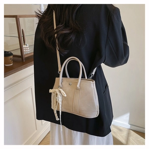 Détail du sac seau blanc crème avec bordure en dentelle et pendentif en perles élégant