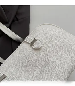 Close-up of white lychee leather texture and premium silver metal hardware on handbag