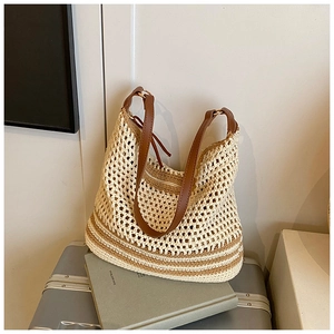 Detail of hollow mesh tote bag with leather handles on a grey suitcase in a lifestyle set
