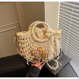 Detail of handmade straw bag with lace bow, colorful floral accents and drawstring liner