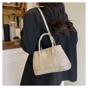 Détail d'un sac seau beige avec boucle métallique et bandoulière dans un décor de café