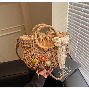 Detailed view of woven straw bag with crochet flowers, lace bow, and drawstring liner