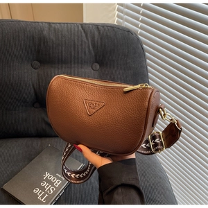 Close-up of brown litchi pattern pillow bag with golden hardware and wide woven strap