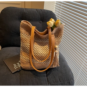 Détail du sac cabas en paille ajouré avec anses en cuir marron et pendentif à glands