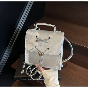 Détail d'un mini sac à dos argenté métallisé avec boucle papillon et perles