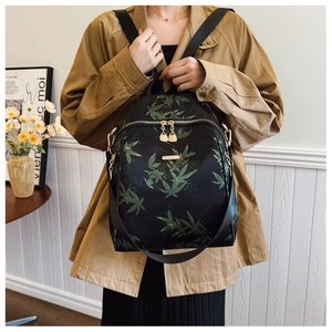 Detail view of black backpack with green bamboo leaf print and golden metal zippers