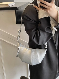 Silver croissant bag with pleated leather design and wide strap shown from a selfie view