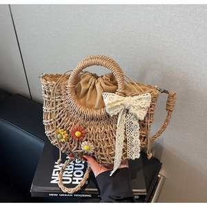 Detailed view of handmade straw bag featuring lace bow and crochet floral accents