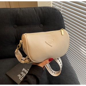 Detail of beige textured leather pillow bag with wide jacquard strap and gold hardware