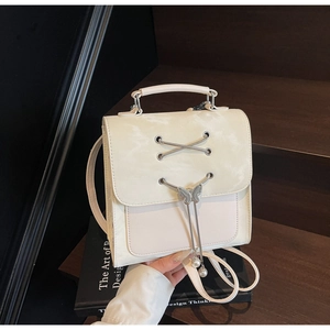 Détail d'un sac à dos vintage crème avec papillon en métal et pompon en perles fines