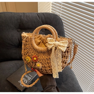 Detail of straw bag featuring lace bow, colorful floral accents and drawstring lining