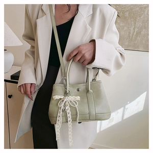 Gros plan d'un sac seau en cuir vert clair avec des nœuds en dentelle et perles sur un modèle