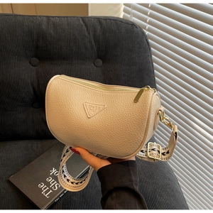 Detail of beige textured pillow bag with wide geometric strap and golden hardware