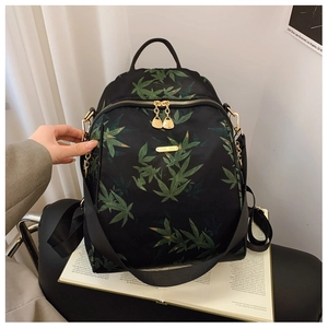 Detail of black canvas backpack with green leaf print and golden metal zippers