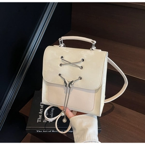 Détail du sac à dos crème avec rubans croisés et pendentif papillon orné de perles fines