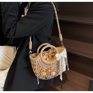 Detail of handwoven straw bag with crochet daisies, lace bow, and drawstring closure