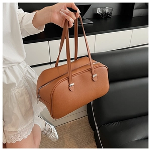 Close-up of brown pebble grain leather surface and silver hardware on Boston handbag