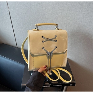 Détail du sac à dos jaune en cuir avec boucle papillon et décoration de franges perlées