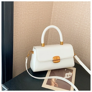 Detail einer weißen Ledertasche mit Rundgriff und elegantem goldenem Vierkantschloss