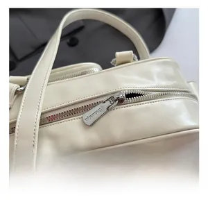 Detail showing high-quality silver metal zipper and smooth cream faux leather material