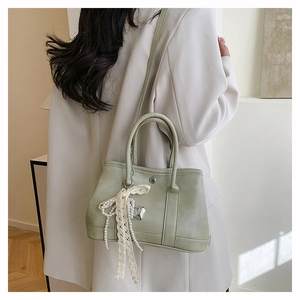 Vue latérale détaillée d'un sac seau en cuir vert sauge avec dentelle et charms