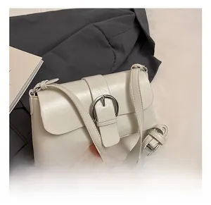 Detail showing the cream oil wax leather texture and silver D-buckle of the shoulder bag