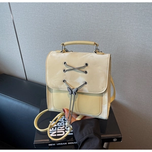 Détail du mini sac à dos jaune clair avec laçage argenté et pendentif papillon en perles