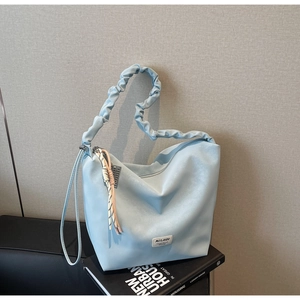 Detail of light blue hobo tote bag featuring a pleated handle and side woven decoration