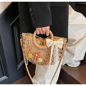 Detail of straw bag with lace bow, floral embroidery and ladybug charm for beach vacations