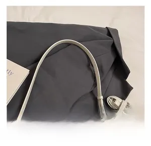 Close-up of beige leather handle and round metal buckle detail on a small square bag